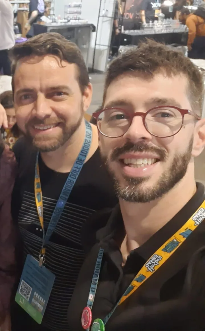 Myke Netto and Yuri Morroni smiling together at a board game fair